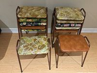 Stacked folding chairs showing floral and solid upholstered cushioned seats, metal frames