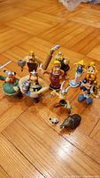 Group photo of the complete set of Asterix and Obelix figurines displayed on wooden floor showing multiple characters including Obelix and Asterix