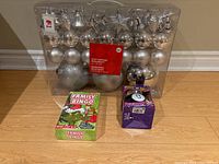 Front image of a set of silver shatterproof Christmas ornaments, Family Bingo game, and Magic 8 Ball game on wooden floor.