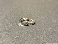 Pair of small silver tone hoop earrings with clear rhinestones, shown on dark neutral background