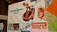 Box cover showing Mario Kart Wii themed Carrera Digital 143 set with image of Mario in a red racing kart and ergonomic controller grip.