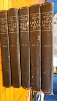 Five spines of volumes I–V showing black cloth binding with silver stamped titles and volume numbers.