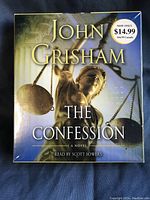 Front cover of the sealed 5-CD audiobook set of 'The Confession' by John Grisham, showing title, author, and imagery of the Lady Justice statue.