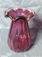 Front and side view highlighting the ribbed cranberry glass and ruffled white rim of the vase.