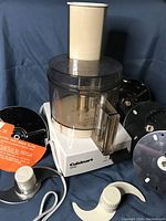 Photo of Cuisinart Basic DLC food processor with multiple metal blades, work bowl, lid with feeder tube and plunger.