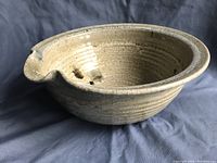 Side view of the large pottery bowl showing the pour spout and textured surface.