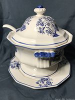 Side view of the closed soup tureen with lid and ladle placed through the handle opening