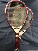Photo showing the front of the two Kawasaki squash racquets laid flat against a dark background, focusing on the frame and stringing.