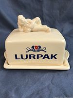 Front view of the ceramic butter dish lid with Lurpak logo and Douglas figurine on top.