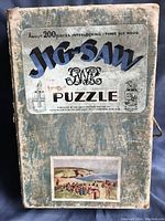 Front view of original puzzle box with printed label and small scene illustration on front