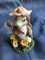 Front view of the whimsical rabbit figurine showing rabbit's face, flower hat with ladybug, butterfly net, and floral base
