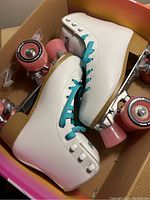 Pair of white women's roller skates size 5 with teal laces, pink wheels, wooden heels inside original box.