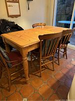 Full view of wooden kitchen table with chairs around it to provide scale. Table top is natural wood, approx 4 ft wide without extension. Extension leaf is installed in photo.