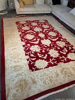 Full view of red and cream floral rug laid on floor between sofas