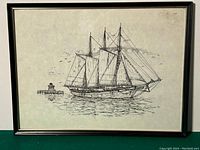 Framed ink drawing of a sailing ship with three masts on the water, showing surrounding sea and distant lighthouse.