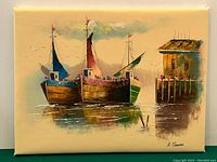 Full view of signed oil painting depicting three fishing boats moored next to a dock with a small building.