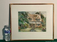 Full framed watercolor painting of an English-style cottage with garden and stone path, next to a water bottle for size reference.