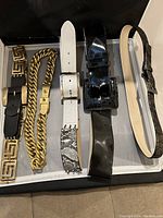 Top view of five vintage ladies belts showing different buckle styles and materials