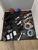 Photo showing the full assortment of cables, plugs, and cable wraps arranged in a box, including braided and standard coaxial cables, black and white USB plugs, and two cable wraps.
