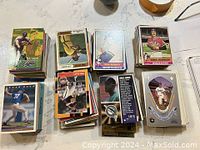Stacks of assorted baseball cards from early 90s and mid 80s to mid 90s, featuring various players and brands.