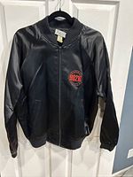 Front view of the black satin-like bomber jacket with front zipper and left chest embroidered Beverly Hills 90210 logo.