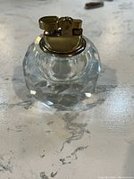 Front view of the vintage hand-cut crystal orb lighter with brass top on a light marble surface.