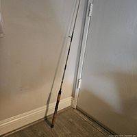 Full view of the 6 1/2 foot Apache fishing rod standing upright indoors, showing overall length and condition.