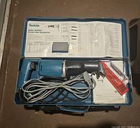 Makita JR3000V reciprocating saw inside open blue carrying case with instruction manual and safety sheet included.
