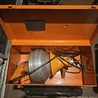 Open carrying case containing the Super-Vee Power Drain Cleaner device with yellow body and silver. Power cord coiled inside the case.