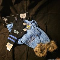 UCLA scarf and gloves with tags and UCLA shot glass on black background