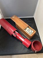 Dominoes inside wooden sliding lid box adjacent to red leather roll-up case for backgammon set, showing dice and pieces