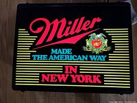 Front view of lighted sign face showing 'Miller' logo, tagline and stripes