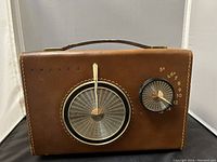 Front view showing the brown leather case, large metal tuning dial, smaller control knob, and PHILCO imprint