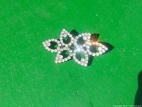 Brooch shown on green background capturing the full floral design and stone details with bright light reflections.