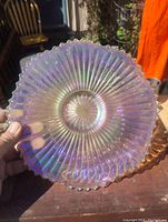 Top view of the iridescent glass plate showing radial ribs and scalloped edges with rainbow-like colors.