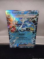 High quality holo foil full art image of the Gyarados EX Pokemon card against a fabric background.