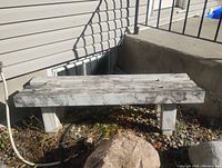 Marble bench placed outdoors near a building, showing the full bench and its supporting legs.