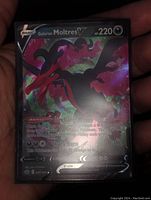Front view of the holo foil full art Galarian Moltres V Pokemon card in hand showing the card art and details.