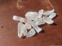 Lot of quartz crystals arranged on a wooden surface, showing size, shape, and transparency.