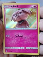 Holofoil Snubbull card held in hand showing front design and attack details.
