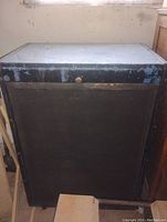 Front view of vintage bass amp speaker cabinet showing black grille and worn blue top and edges with paint chipping.