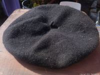 Top view of black wool smock hat showing the gathered crown and texture of the fabric.