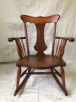 Front view of the antique wooden rocking chair showing the carved backrest and wide seat.