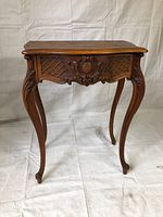 Front view of antique wooden side table showing carved apron, cabriole legs and top surface.