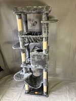 Front view of the entire grey cat tower showing multiple platforms, hammock, scratching posts, and top area with dangling balls.