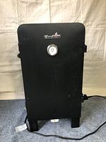 Front view of the closed black Char-Broil electric smoker with temperature gauge on the door.