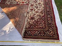 Corner view of ivory and red floral runner rug showing fringe and backing