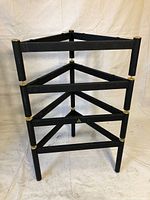 Front view of the stacked four black metal frames with triangular supports forming audio stand.