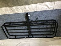 Top-down view of black metal hitch cargo carrier rack flat on surface, showing rectangular frame and hitch mount.
