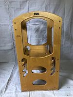 Front view of wooden learning tower showing opening, side cutouts, and stable base.